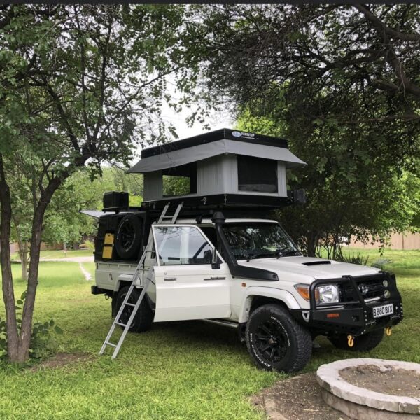 A white truck with an open roof is parked in the grass.