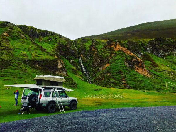 A car parked on the side of a road near some mountains.