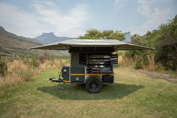 A trailer with an awning and a grill on the back.