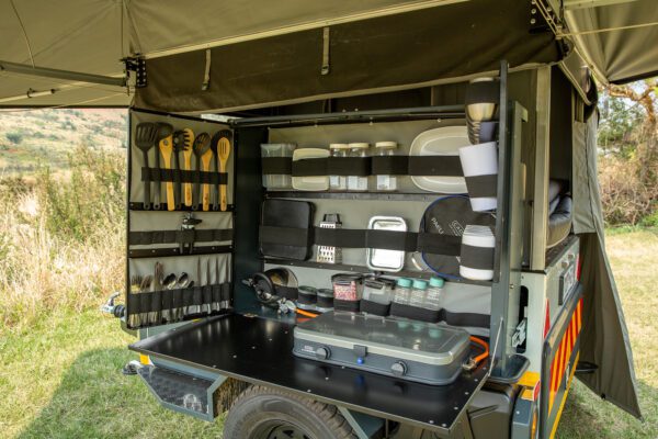 A camper trailer with an open door and shelves