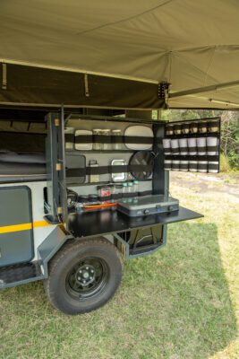 A camper trailer with an open door and shelves.