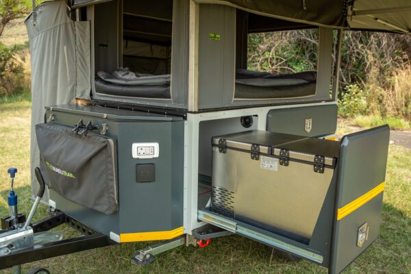 A tent trailer with an open door and storage compartment.