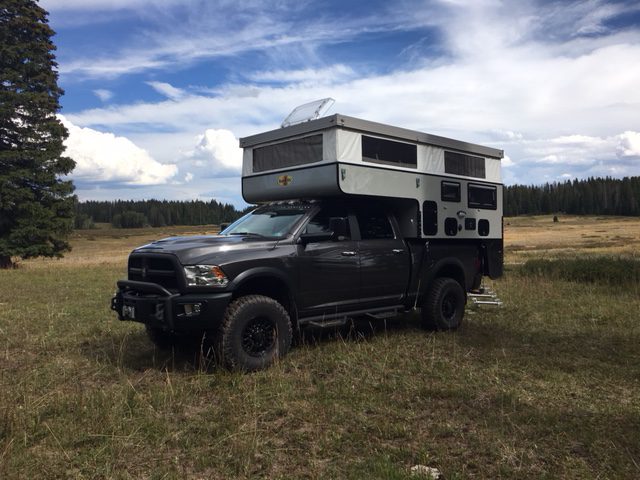 A truck with an rv on top of it in the middle of nowhere.