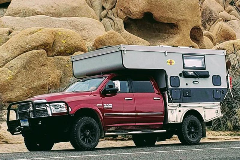 A red truck with an rv on top of it.