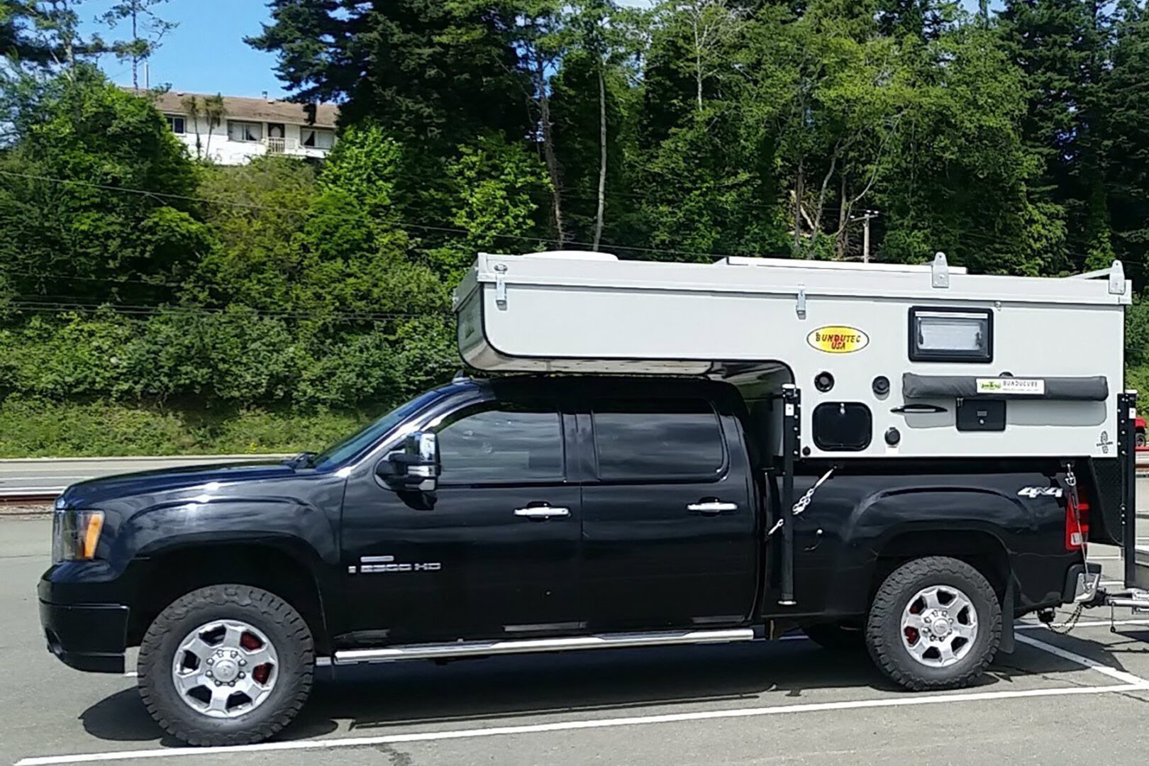 A black truck with a camper on top of it.
