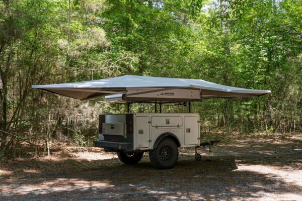 A camper trailer with an awning attached to it.