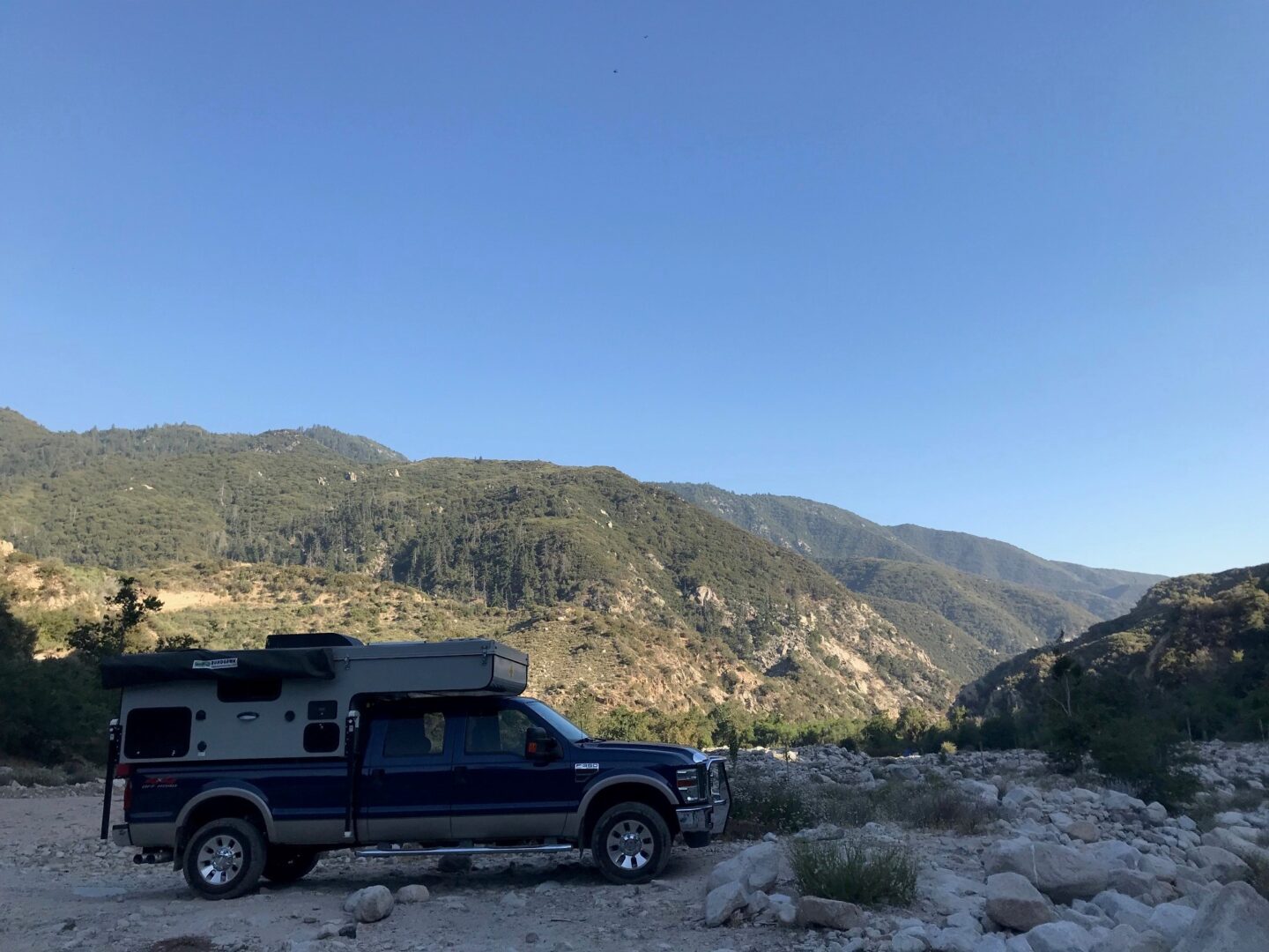 A truck parked in the desert with a camper on top.