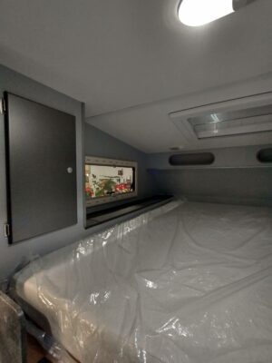 A bed with white sheets and a tv on the wall.