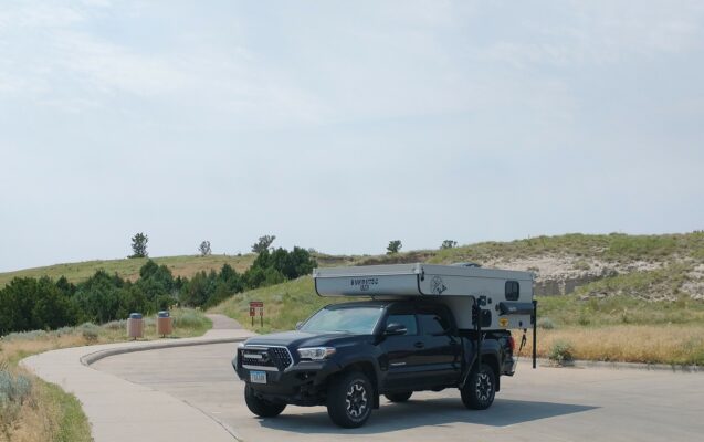 A black truck with a tent on the back of it.