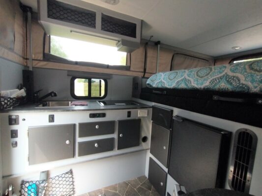 A kitchen with a sink, oven and refrigerator.