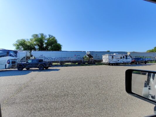 A truck is parked in the parking lot near a trailer.