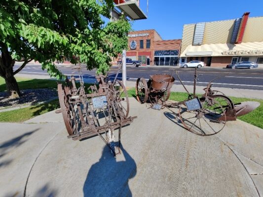 A couple of old farm equipment sitting on the side of a road.