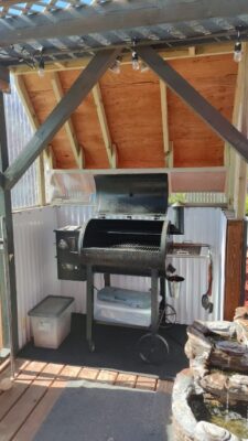 A grill in the middle of an outdoor shed.