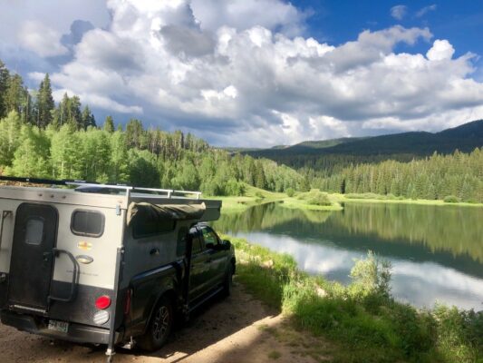 A camper is parked next to a lake.