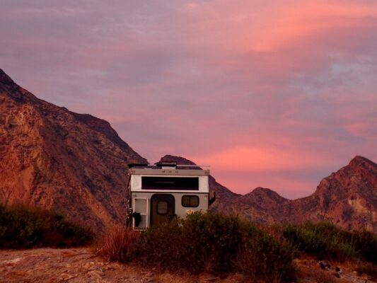 An rv sits on top of a mountain at sunset.