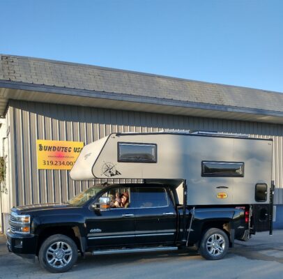 A truck with a camper parked in front of a building.