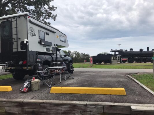 An rv parked next to a train track.