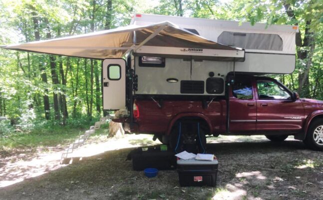 A red truck with a camper attached to it.