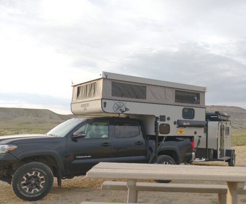 A black truck with a camper attached to it.