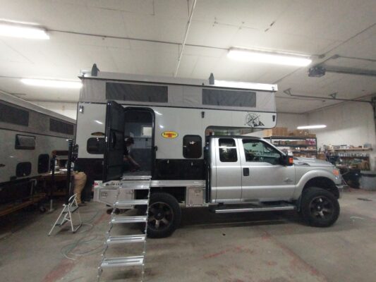 A truck with a camper on top of it in a garage.