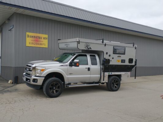 A truck with a camper parked in front of a building.