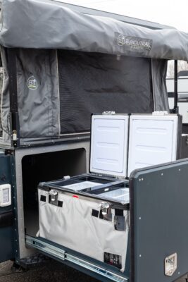 A camper trailer with a cooler in the back.