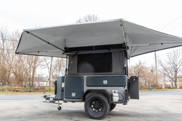 A camper trailer with a canopy on the side.