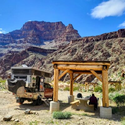 A camper is parked in the desert near a mountain.