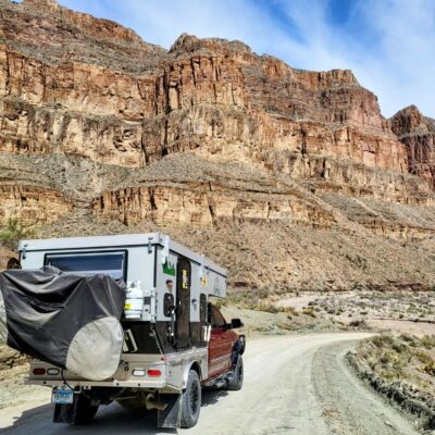 An rv is parked on a dirt road near a mountain.