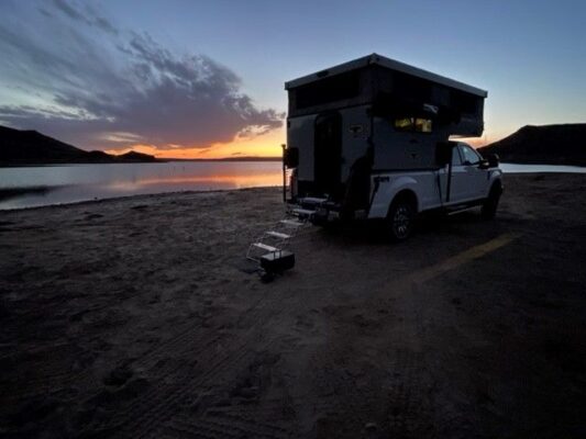 An rv parked on the beach at sunset.