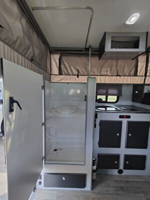 The interior of an rv with a sink and refrigerator.