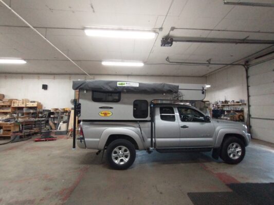 A toyota tacoma with a camper parked in a garage.