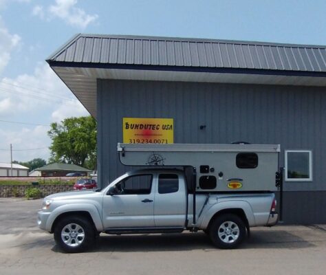 A truck with a camper parked in front of a building.