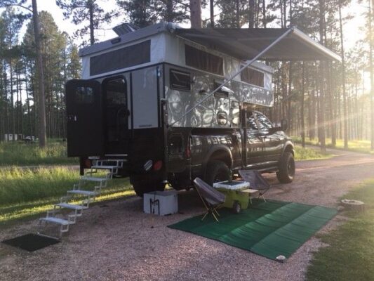 A camper truck parked in a wooded area.