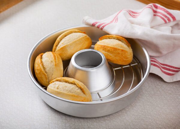 A baking rack with rolls in it.