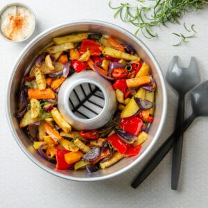 A baking rack with vegetables in it and a fork next to it.