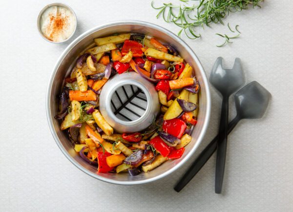 A baking rack with vegetables in it and a fork next to it.