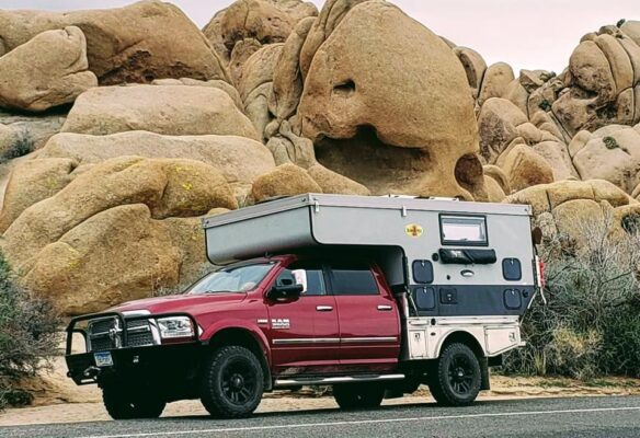 A truck with a camper parked on the side of a road.