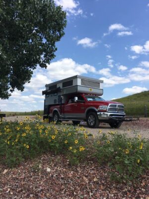 A ram truck with a camper parked on the side of the road.