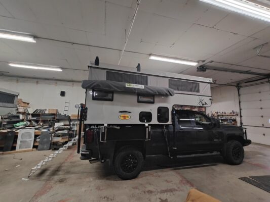 A black truck with a camper parked in a garage.