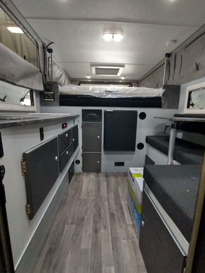 The interior of a camper van with a bed and a kitchen.