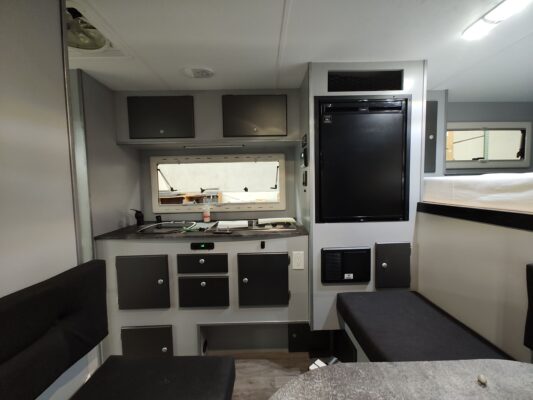 The interior of an rv with a kitchen and a bed.