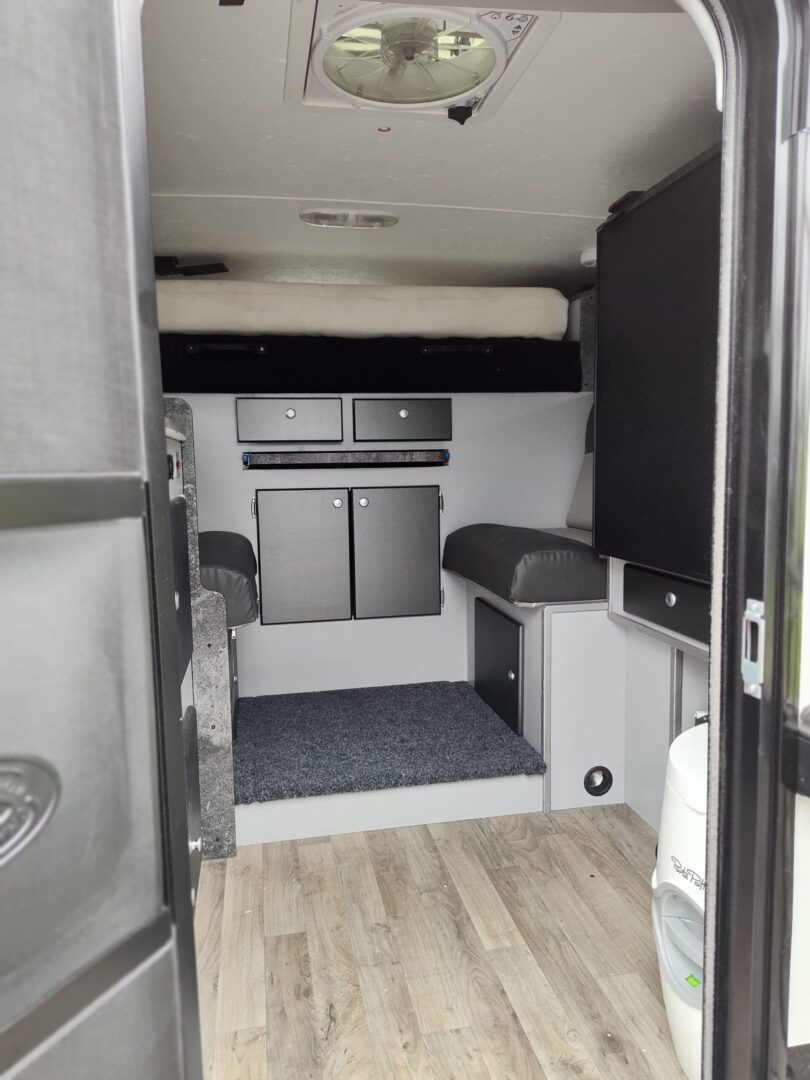 The interior of an rv with a bed and a sink.