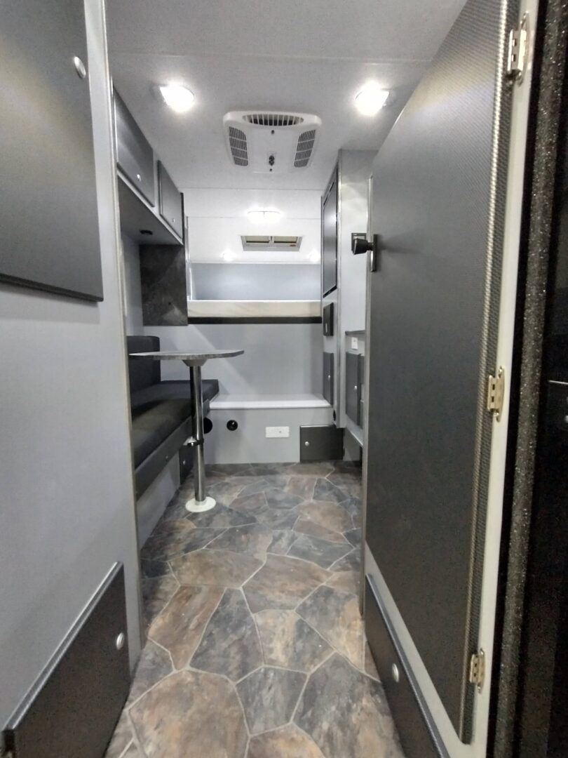 The interior of an rv with a bed and a sink.