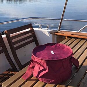 A maroon cloth bag sitting on a wooden table on a boat.