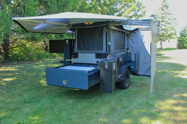 A camper trailer with a tent on top of it.