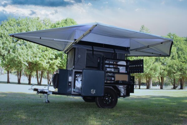 A camper trailer with a tent on top of it.