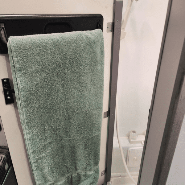 Green towel hanging on a rack in bathroom.