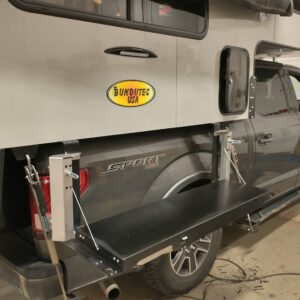 Truck with a pop-up camper and a side table.