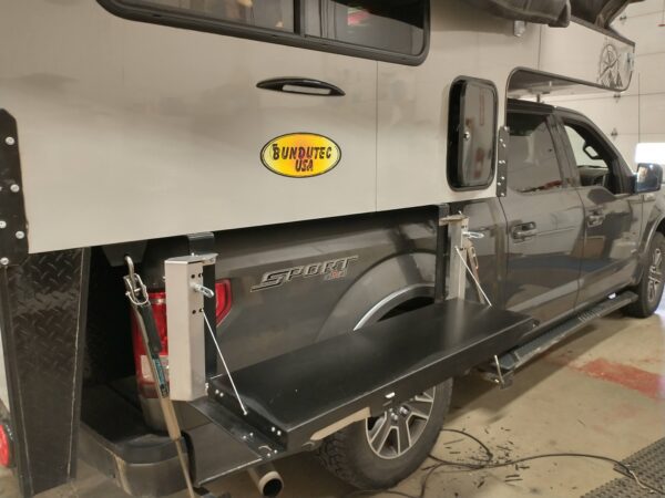 Truck with a pop-up camper and a side table.